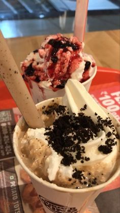 an ice cream sundae with toppings in a paper cup on a table top