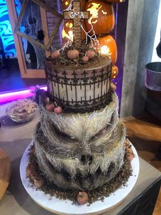 a three tiered halloween cake with pumpkins on the side and decorations around it