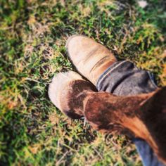 a person's feet and boots in the grass