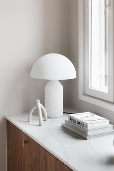 a white lamp sitting on top of a counter next to a book