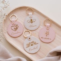 three personalized leather keychains on a wooden tray with pink and white flowers