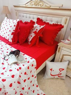 a bed with red and white sheets, pillows and eyeglasses on top of it