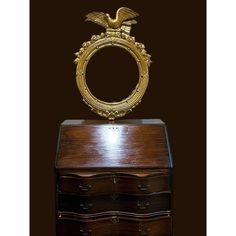 an ornate gold framed mirror sitting on top of a wooden chest with drawers underneath it