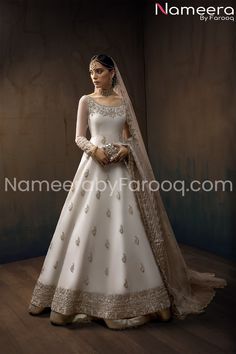 a woman in a white wedding gown with gold accents on her head and veil over her shoulder