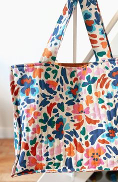 a multicolored floral bag hanging from a white chair