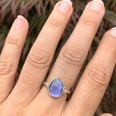 A vibrant purple Iolite is set between two brilliant white diamonds. Set in 14k yellow gold with a sterling silver seagrass band this ring will quickly become a favorite. Approx stone size: 13mm x 10mm Approx stone weight: 2.4cts Mohs Hardness: 7-7.5 This one of a kind piece is handmade with love in Emily's Hudson Valley studio. If you have questions about sizing, shipping or need help deciding on your perfect piece please reach out to us! Tanzanite Birthstone Ring In Fine Jewelry Style, Fine Jewelry Tanzanite Birthstone Ring, Diamond Rings With Gemstone Accents For Promise, Diamond Promise Rings With Gemstone Accents, Bezel Set Tanzanite Jewelry For Anniversary, Tanzanite Gemstone Rings In Yellow Gold, Yellow Gold Tanzanite Gemstone Rings, Anniversary Tanzanite Jewelry With Bezel Setting, Yellow Gold Sapphire Ring In 14k White Gold