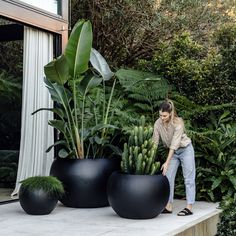 a woman standing next to two large black planters