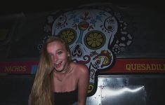 a woman with long hair standing in front of a wall decorated with sugar skull decorations