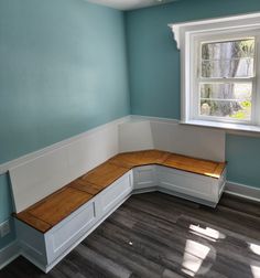 a corner bench in the corner of a room with blue walls and wood flooring