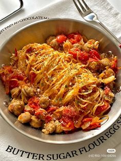 a bowl filled with pasta and meat on top of a white cloth next to a fork