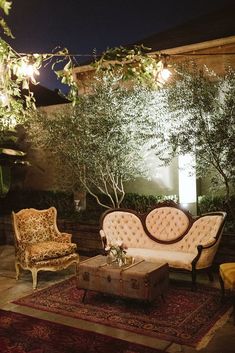 a living room with couches, chairs and tables in the middle of it at night