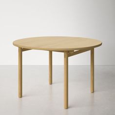 a wooden table with two legs and a circular shape on the top, in an empty room