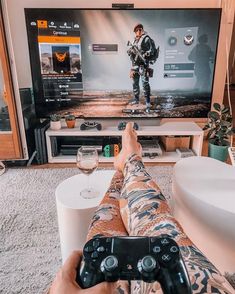 a person holding a game controller in front of a flat screen tv with an image of a soldier on it