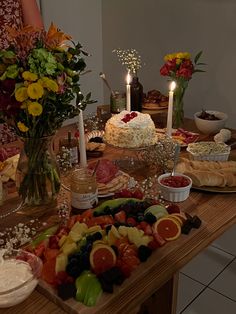 a wooden table topped with lots of different types of food and candles on top of it