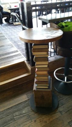 a stack of books sitting on top of a wooden table next to a metal stool