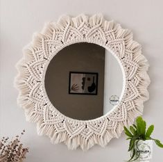 a round mirror hanging on the wall next to a potted plant