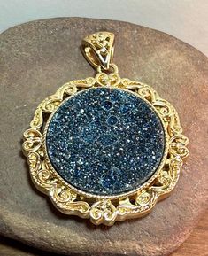 This is a beautiful, vintage, genuine, Beria Collection 18K yellow gold overlay, blue and black druzy quartz and bronze pendant that has stunning and ornate scrollwork. The pendant features a sparkly, natural, genuine blue and black druzy quartz that is round-cut in its center. There is a gorgeous and ornate cutout design surrounding the druzy that has scrollwork hearts and other scrollwork designs. There is also an open scrollwork design on the back of the pendant. The pendant measures about 1 7/8" long by 1 1/2" wide (About 1 1/2" in diameter without its bale). The bale opening is a little more than 1/4" in length. The pendant is so pretty. The pendant weighs about 20.5 grams and is stamped BC 18K Bronze, which is the hallmark for Beria Collection. The pendant also has been tested and is Druzy Quartz, Bronze Pendant, Boho Gifts, Quartz Pendant, Handmade Artisan, Druzy, Antique Jewelry, 18k Gold, Vintage Jewelry