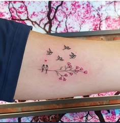 a woman's arm with birds and flowers tattoo on the left side of her arm