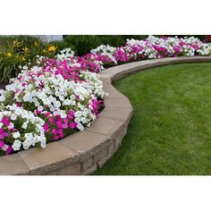 a flower garden with white and pink flowers in the center, surrounded by green grass