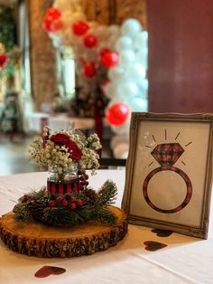 a table topped with a vase filled with flowers next to a picture frame on top of a wooden slice