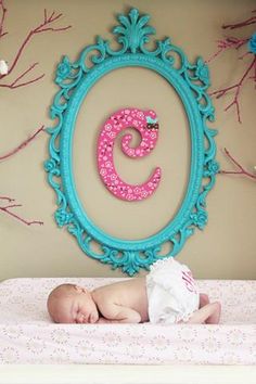 a baby laying on its stomach in front of a blue frame with the letter c