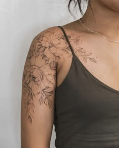 a woman wearing a tank top with flowers on her arm and chest tattooing it