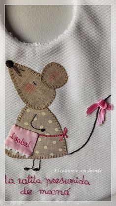 a white bib with a pink ribbon on it and a mouse embroidered on the front