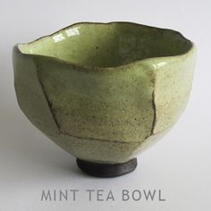 a green bowl sitting on top of a wooden stand