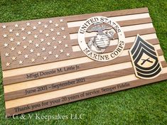 an american flag with the marine service emblem on it is laying in the grass next to a plaque that reads,'thank you for your 20 years of service since