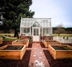 several wooden planters in front of a white house with glass doors and windows on the side