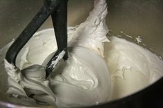 a metal bowl filled with whipped cream and two black tongs