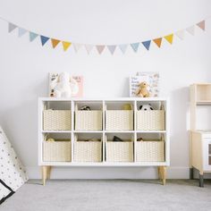 a white shelf filled with baskets next to a baby's crib and stuffed animals