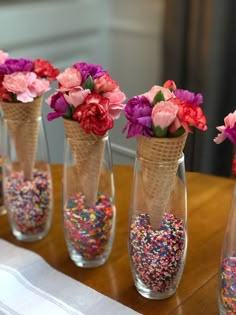 vases filled with flowers and sprinkles on top of a wooden table