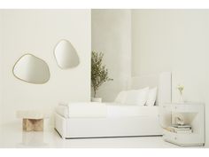 a white bedroom with two mirrors on the wall and a plant in the corner next to it