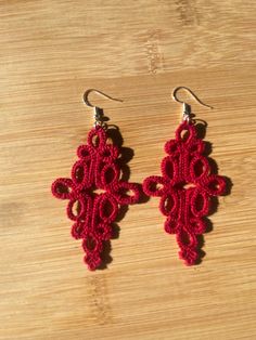 two pairs of red crocheted earrings sitting on top of a wooden table