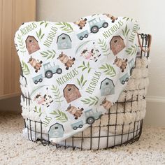 a baby blanket with farm animals on it is sitting in a basket next to a door