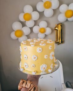 a yellow cake sitting on top of a table next to balloons and a number one