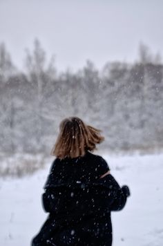 a woman walking in the snow with her back to the camera and looking at something