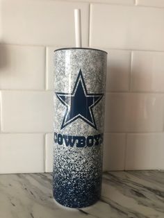 a blue and white tumbler sitting on top of a counter next to a tiled wall