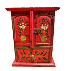 an old red painted wooden cabinet with flowers and leaves on it's door handle