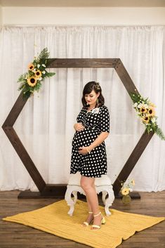 a woman standing in front of a wooden frame with sunflowers