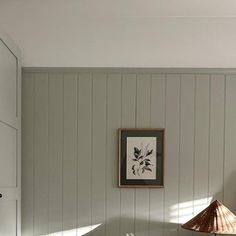 a room with white walls and wood paneling on the wall, along with a lamp