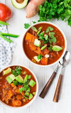 two bowls of chili soup with avocado and tomatoes