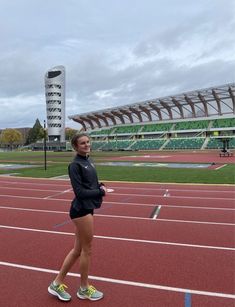 a woman standing on a track in front of an empty stadium