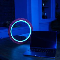 a laptop computer sitting on top of a wooden table in front of a blue light