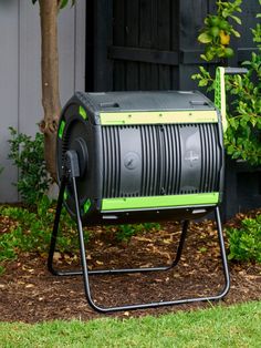 a green and black cooler sitting on top of a metal stand next to a tree