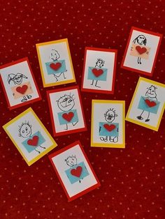 small cards with pictures of people and hearts are arranged on a red tableclothed surface