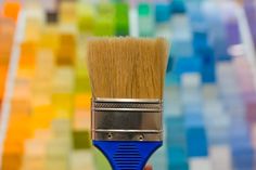 a close up of a paint brush with multicolored tiles in the back ground