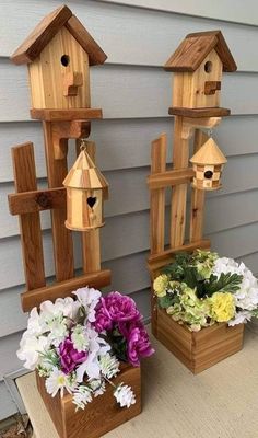 two wooden bird houses sitting on top of a table next to flowers and greenery