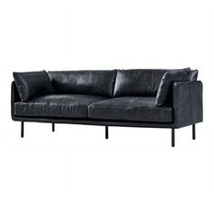 a black leather couch sitting on top of a white wall